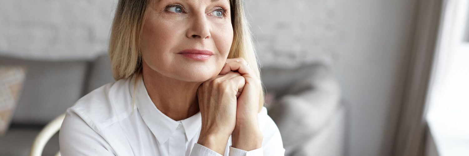 An older adult woman, a population that may have autism and not realize it, sits in deep thought.