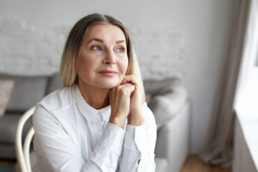 An older adult woman, a population that may have autism and not realize it, sits in deep thought.