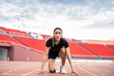 Asian young sportswoman sprint on a running track outdoors on stadium.