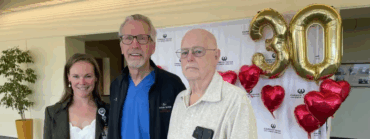 Patient stands with members of his care team at Carson Tahoe Health during a heart surgery reunion celebration, with 30th anniversary balloons in the background.