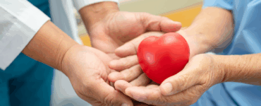 Healthcare professional and patient holding a red heart symbolizing heart health and compassionate care.