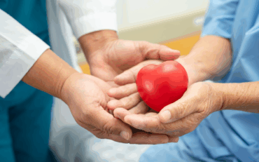 Healthcare professional and patient holding a red heart symbolizing heart health and compassionate care.