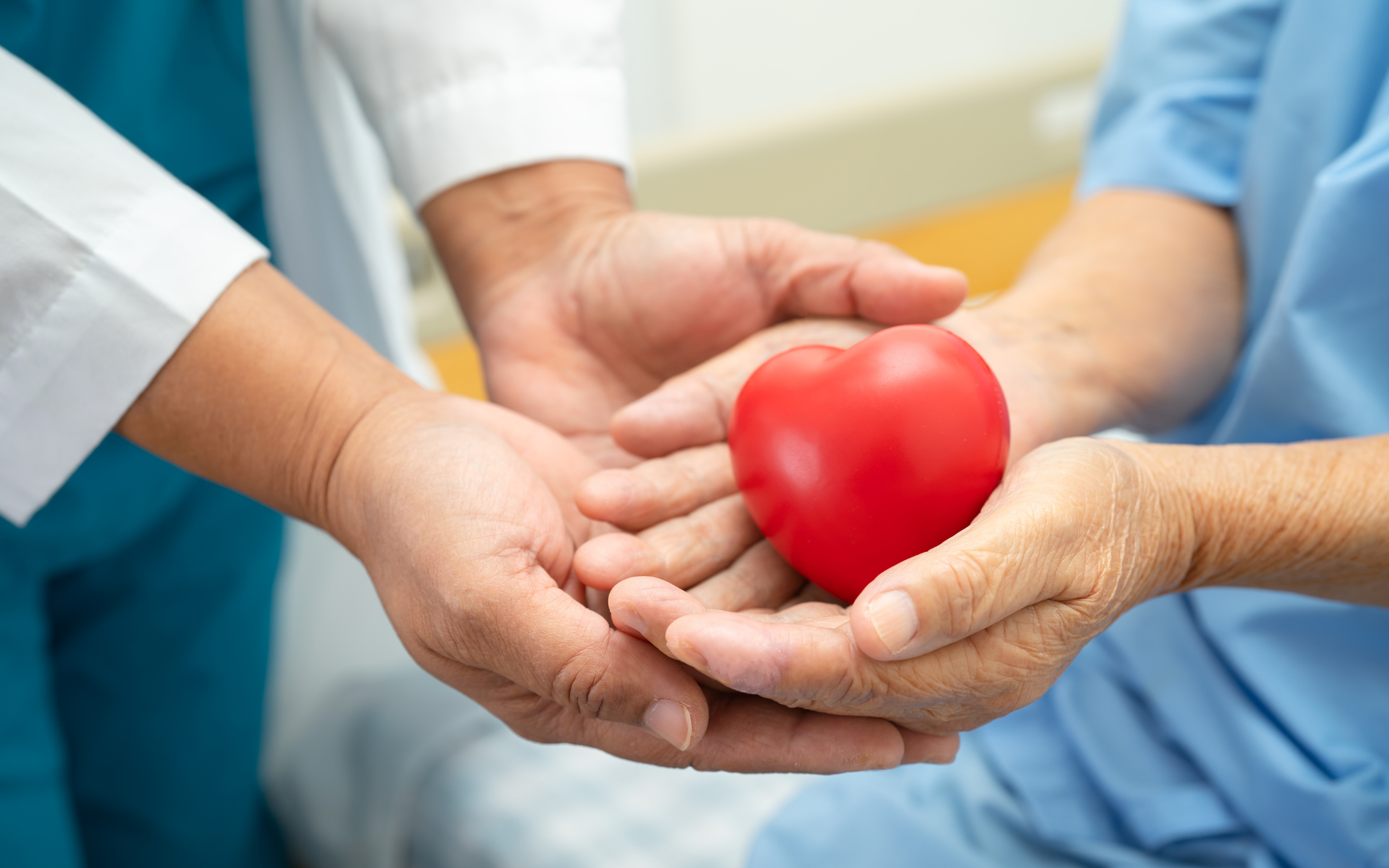 Healthcare professional and patient holding a red heart symbolizing heart health and compassionate care.