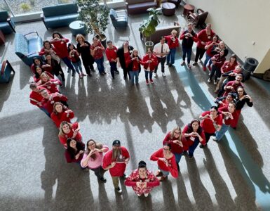 Staff wearing red form a heart shape in a hospital lobby for National Wear Red Day