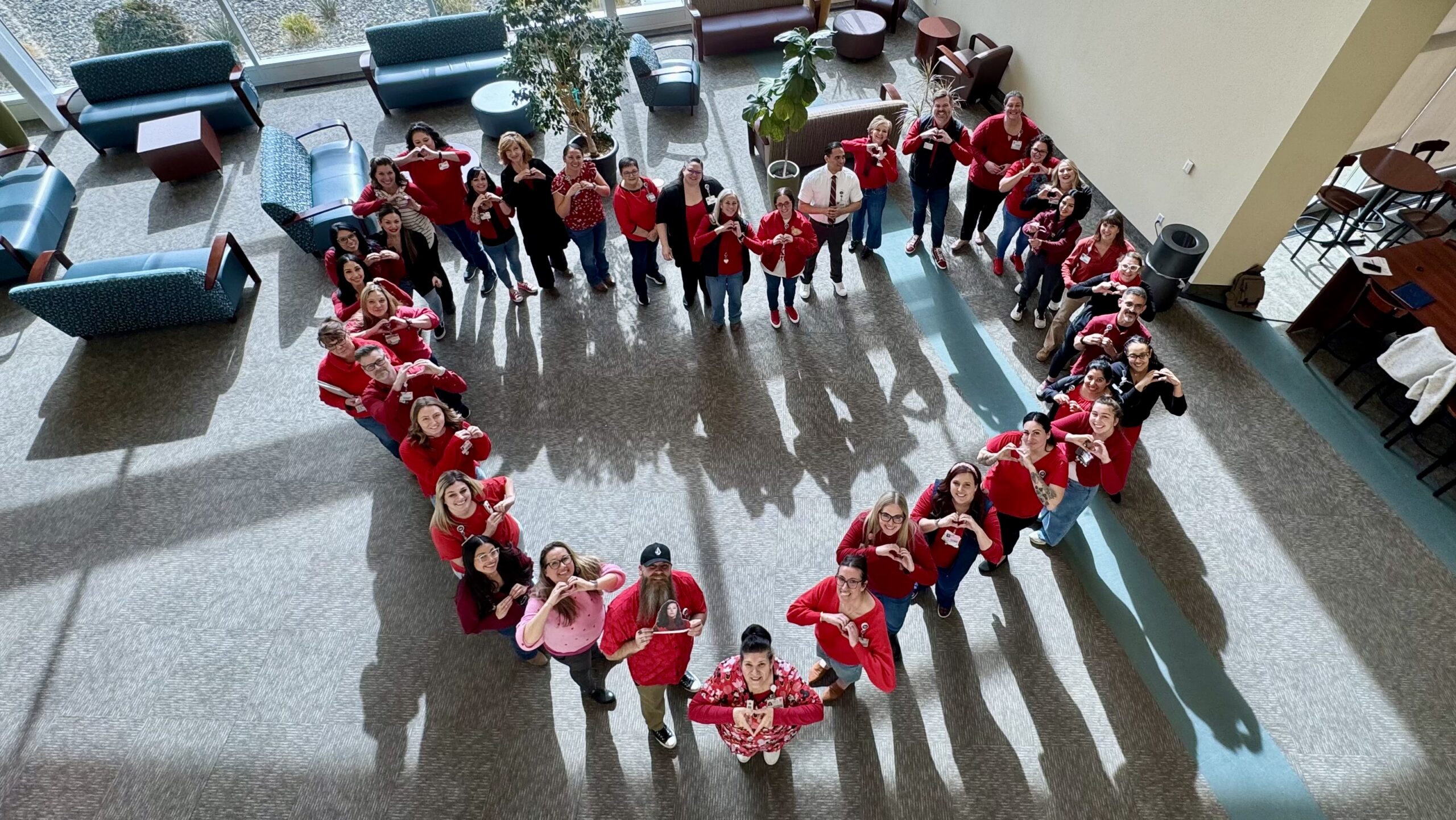 Staff wearing red form a heart shape in a hospital lobby for National Wear Red Day
