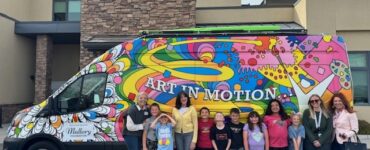 Children and staff standing in front of the colorful “Art in Motion” Vehicles of Change van at a Carson Tahoe Health youth mental health program.