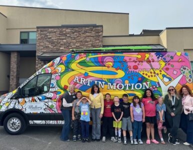 Children and staff standing in front of the colorful “Art in Motion” Vehicles of Change van at a Carson Tahoe Health youth mental health program.