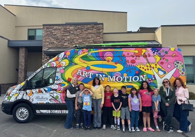 Children and staff standing in front of the colorful “Art in Motion” Vehicles of Change van at a Carson Tahoe Health youth mental health program.