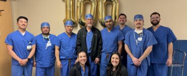 Carson Tahoe Health cardiovascular team celebrating 100th TAVR procedure milestone with staff standing in scrubs in front of gold 100 balloons