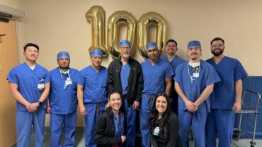 Carson Tahoe Health cardiovascular team celebrating 100th TAVR procedure milestone with staff standing in scrubs in front of gold 100 balloons