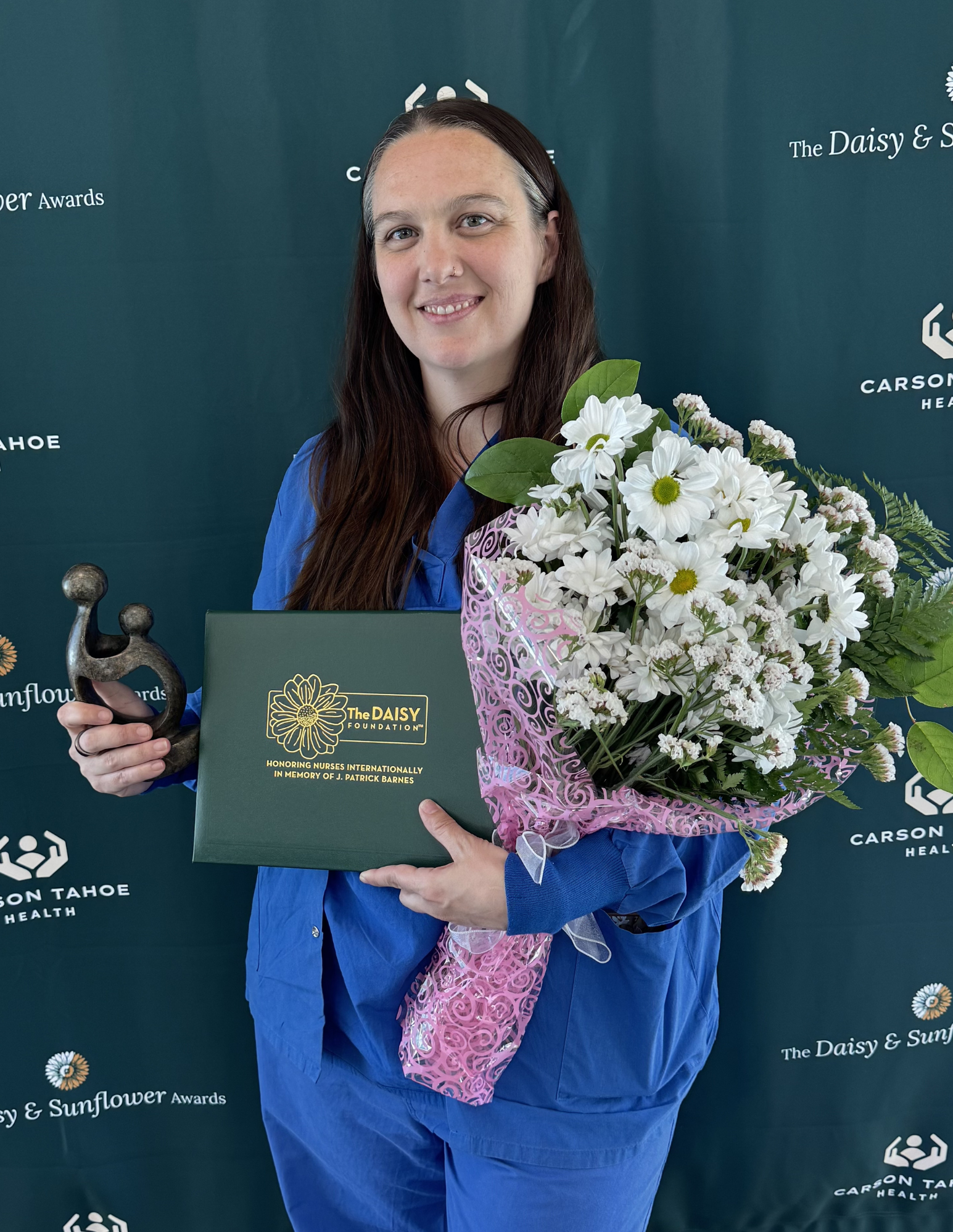 Sarah Jensen holding DAISY Award certificate and flowers at Carson Tahoe Health recognition event