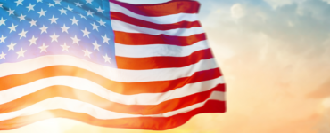 American flag waving in the wind against a sunset sky, symbolizing Independence Day and patriotism