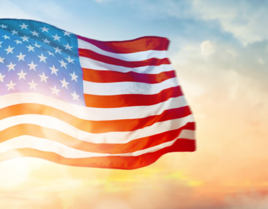 American flag waving in the wind against a sunset sky, symbolizing Independence Day and patriotism