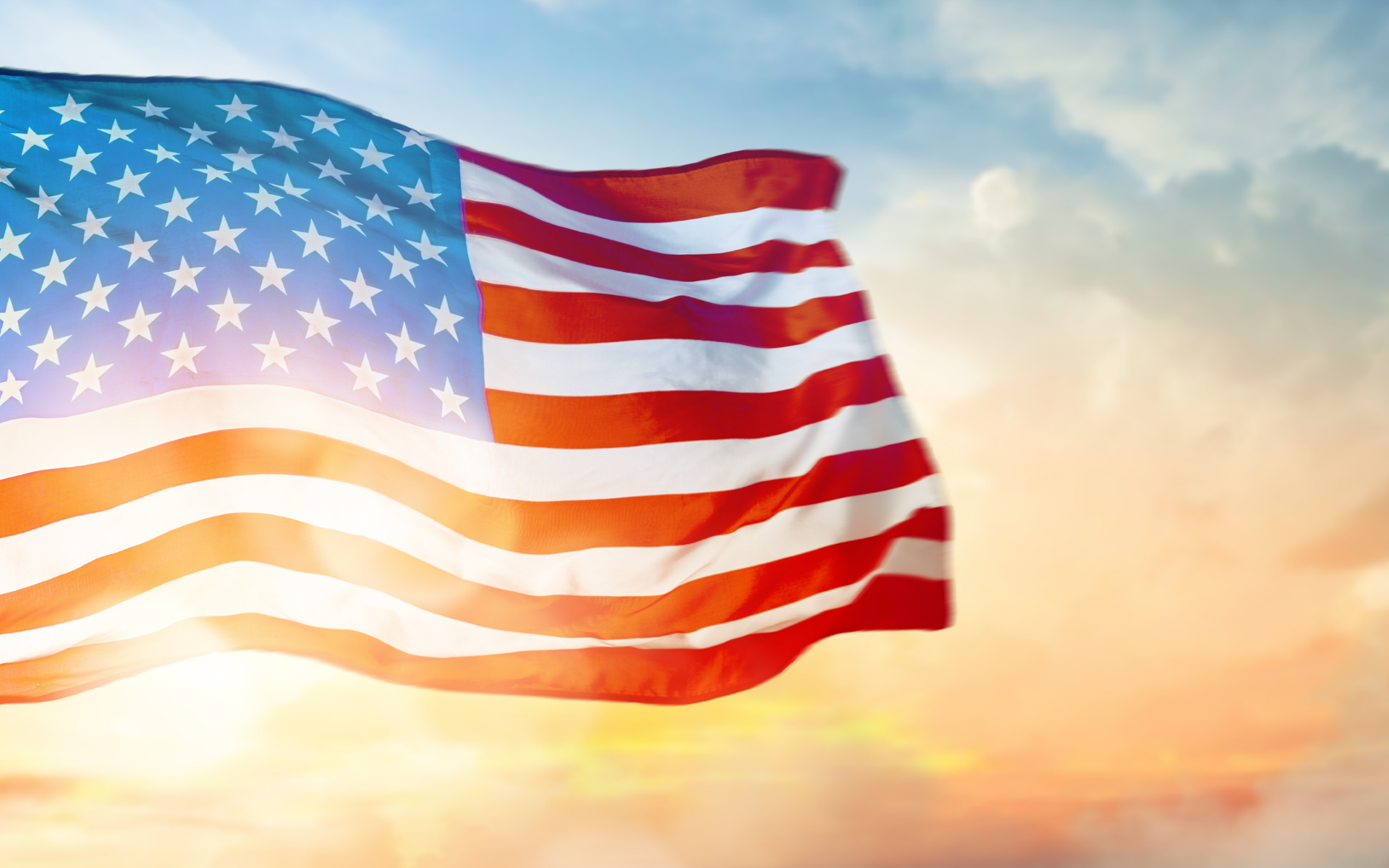American flag waving in the wind against a sunset sky, symbolizing Independence Day and patriotism