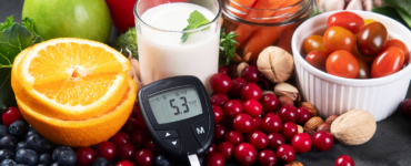 Healthy foods including fruits, vegetables, nuts, and milk with a glucose meter showing blood sugar levels, representing diabetes prevention and healthy lifestyle