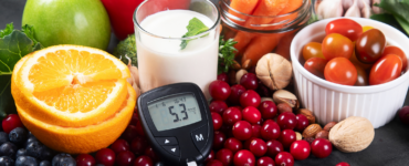 Healthy foods including fruits, vegetables, nuts, and milk with a glucose meter showing blood sugar levels, representing diabetes prevention and healthy lifestyle