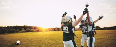 High school football players celebrating on field during practice, representing student athletes preparing for sports season