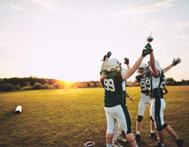 High school football players celebrating on field during practice, representing student athletes preparing for sports season