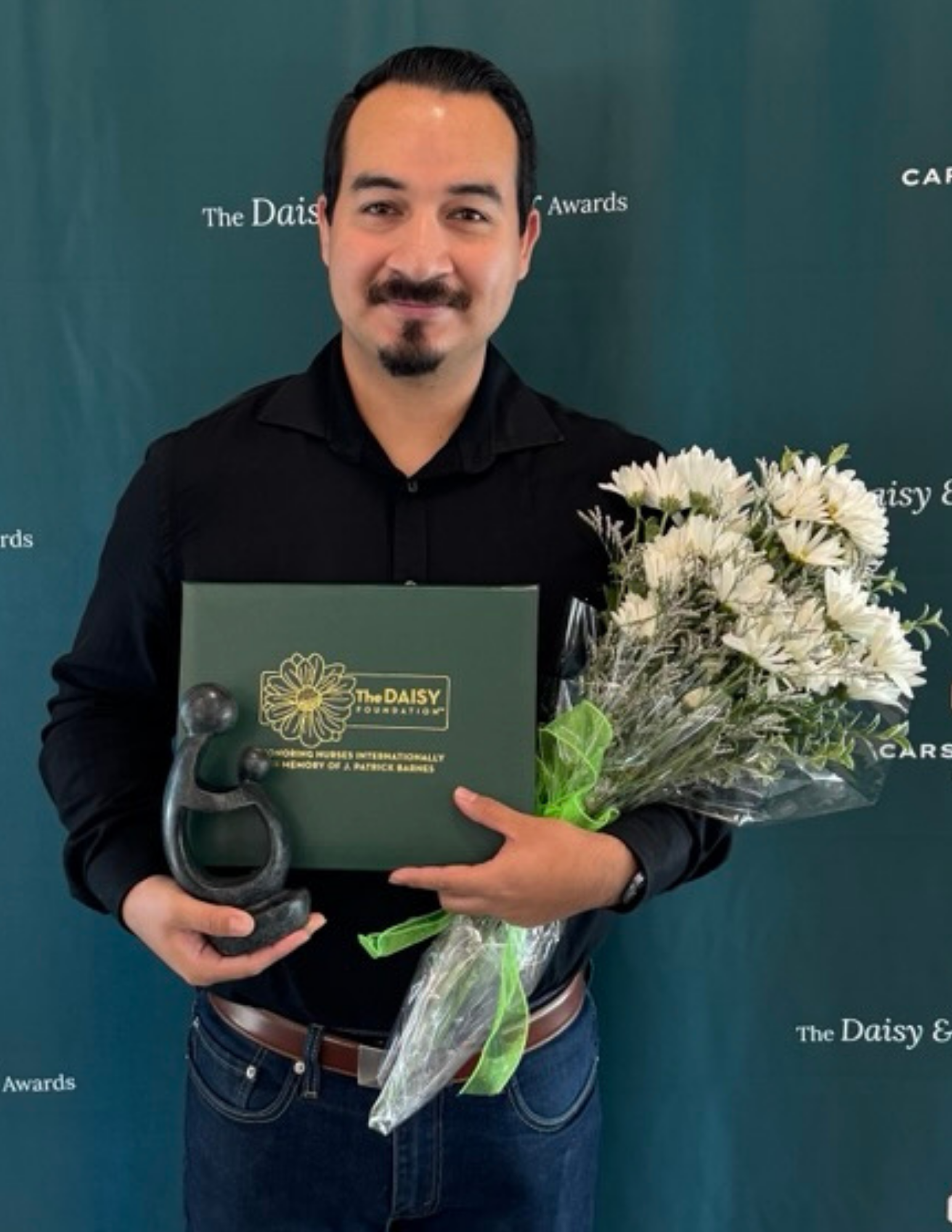 Juan Juarez Razo holding his DAISY Award and flowers at Carson Tahoe Health