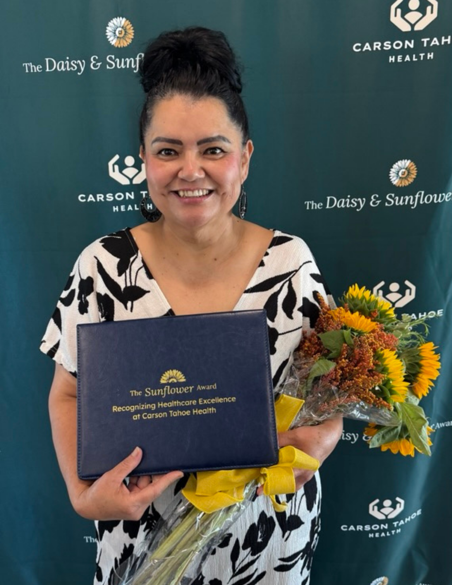 Alba Alegria holding her Sunflower Award and a bouquet of sunflowers at Carson Tahoe Health
